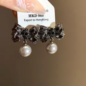 Close-up view of vintage style wrinkled bow pearl drop earrings held on a display card