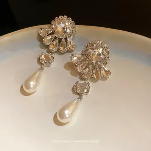 Pendientes de flores de plata con cristales y perlas de gota en plato blanco