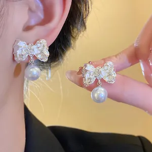 Detailed close-up shot of crumpled silver bow earrings with elegant pearl pendants.