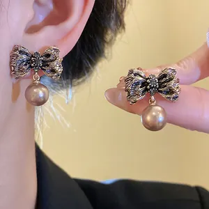 Detailed view of vintage wrinkled metal bow earrings with elegant pearl drop charms.