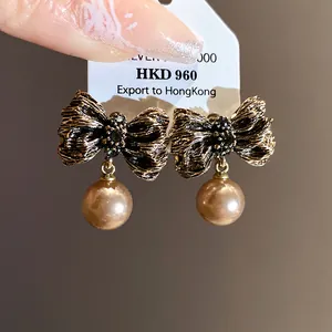 Close-up of vintage pleated bowknot earrings with champagne pearl drops