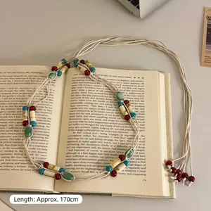 Detailed view of a long bohemian style beaded waist chain with colorful accents over book