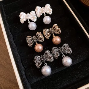 Close-up detail showing exquisite wrinkled bow earrings with elegant pearl pendants in a box