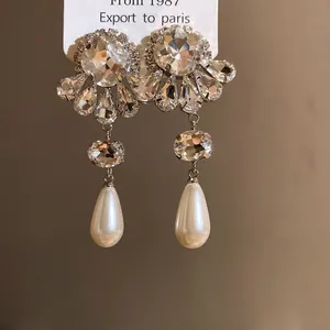 Vista detallada de pendientes de flor con diamantes de imitación y perlas.