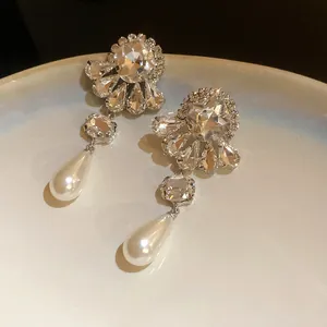 Detalle macro de elegantes pendientes de flor de cristal con perlas de gota refinadas