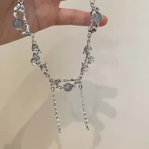 Detailansicht der silbernen Halskette mit blauen Perlen und Strass-Blumenanhänger