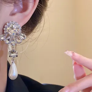Primer plano de elegantes pendientes de plata con diamantes y perlas en gota