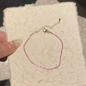 Close-up view of a delicate pink square zircon bracelet featuring a fine gold-tone chain