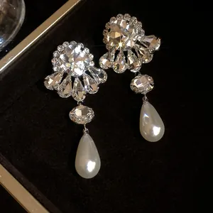 Primer plano de pendientes colgantes con flores de diamantes de imitación y perlas de gota