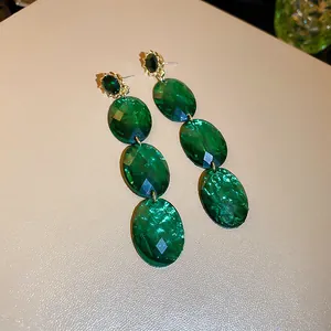 Close-up of vintage emerald green oval faceted crystal drop earrings with gold finish