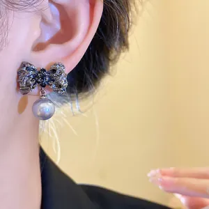 Detailed view of vintage wrinkled bow earrings with a silver pearl pendant on ear