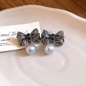 Close-up detail of vintage pleated silver bow earrings with elegant grey pearl drops