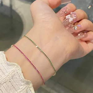 Close-up of elegant ultra-thin square cubic zirconia bracelets in magenta and emerald green