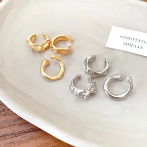 Detailed view of irregular textured and smooth minimalist ear cuffs in gold and silver finish