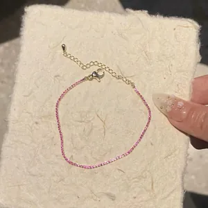 Close-up of fine pink square zircon bracelet with elegant gold-plated chain details