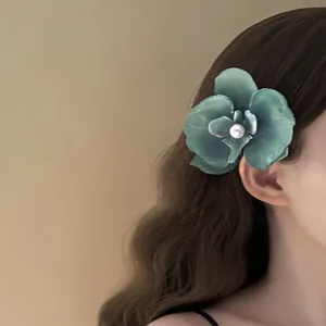 Teal phalaenopsis orchid flower hair clip with elegant pearl center on wavy brown hair