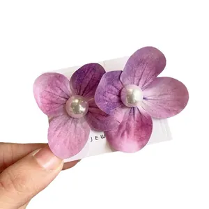 Elegant purple orchid flower hair clip with pearl detail on a display card for women