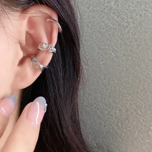 Close-up of silver irregular 3-piece ear cuff set on model's ear showing metal texture.