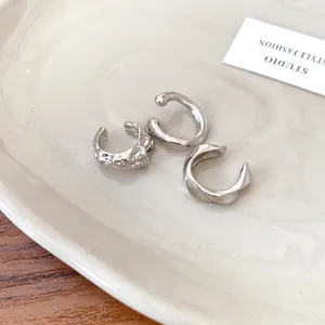 Close-up of three irregular silver ear cuffs with hammered and smooth textures