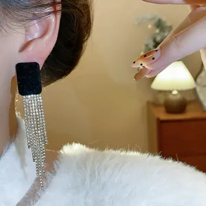 Close-up of model wearing flocked square stud earrings with sparkling rhinestone tassels