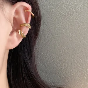 Close-up view of three stylish gold ear cuffs set worn on a model's ear cartilage