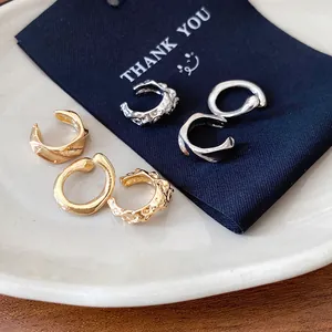 Detailed macro view of textured irregular gold and silver metallic ear cuffs on a thank you card