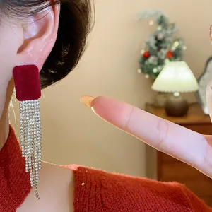 Close-up view of red velvet square earrings with long sparkling rhinestone tassels