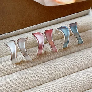 Κοντινό πλάνο τριών ζευγαριών ακανόνιστων σκουλαρικιών σμάλτου σε σχήμα C σε κουτί