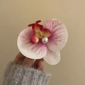 Close-up view of an elegant pink phalaenopsis orchid hair clip with a center pearl detail