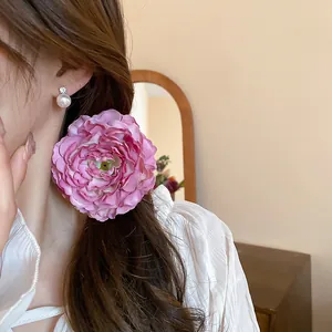 Detailed view of a romantic pink fabric flower hair clip worn as a side hair accessory