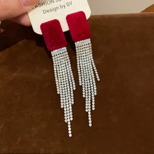 Detailed close-up of red flocked square earrings with shimmering rhinestone tassels