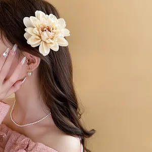 Detailed close-up view of an elegant cream floral hair clip styled on side swept hair.