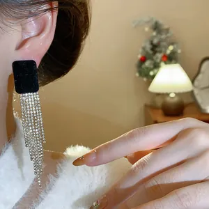 Close-up view of black flocked square stud earrings with long shimmering rhinestone tassels