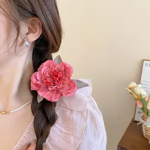 Close-up detail of a large pink fabric flower hair clip worn in a braided hairstyle