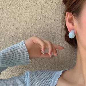 Elegant light blue resin teardrop stud earrings worn on model for a chic look
