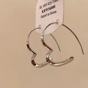 Close-up of minimalist S925 silver heart-shaped hoop earrings with product tag