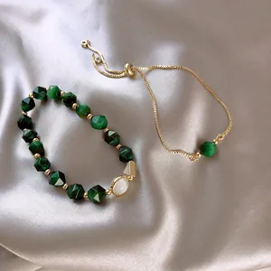 Nahaufnahme eines eleganten grünen Edelstein-Armband-Sets auf Seide