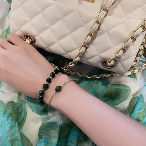 Elegante Nahaufnahme eines grünen Edelstein-Armbandsets an einem Handgelenk mit Tasche