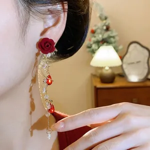 Eleganti orecchini a nappa con rosa rossa floccata festiva con perle e cristalli sulla modella