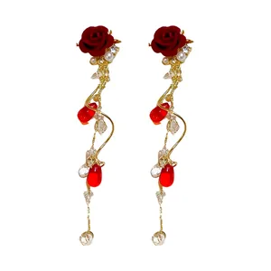 Eleganti orecchini pendenti con rosa rossa floccata, perle e cristalli con nappe dorate
