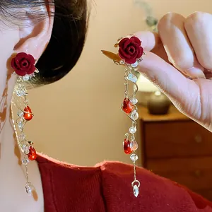 Orecchini a pendolo con rosa rossa floccata, perle e cristalli scintillanti.