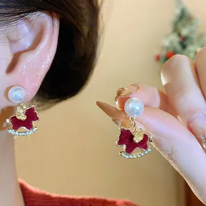 Detailed view of red rocking horse stud earrings with pearl and rhinestone accents