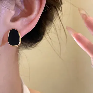 Elegant French vintage style black enamel drip oil stud earrings with gold border on model