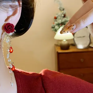 Primo piano di eleganti orecchini a rosa rossa floccata con nappe di perle e cristalli