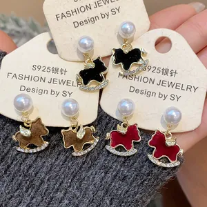 Elegant S925 silver rocking horse earrings with pearls and crystals on grey knit cloth.