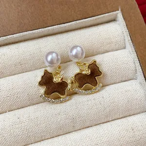 Close-up of brown flocked rocking horse earrings with pearl stud and rhinestones
