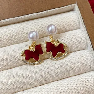 Detail view of elegant gold-plated rocking horse earrings with white pearls and red velvet finish.