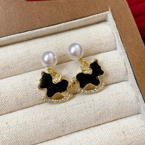 Close-up detail of elegant rocking horse earrings with black enamel and white pearls