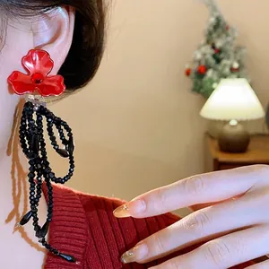 Elegant floral stud earrings featuring layered black bead tassels and a vibrant red crystal accent