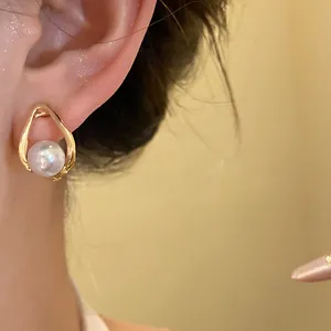 Close-up view of elegant gold water-drop earrings with white pearl detail for women